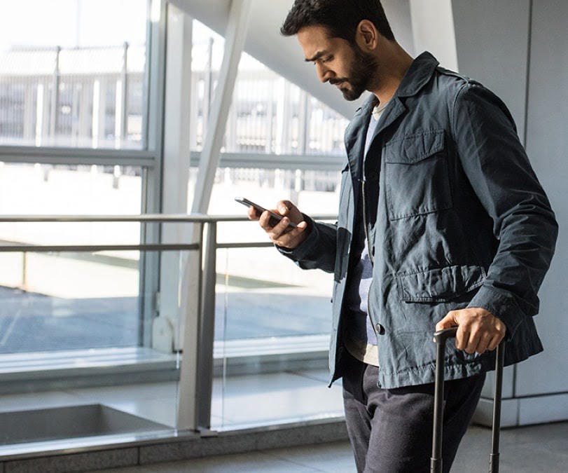 Man standing at airport while looking at his phone